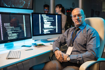 Poster - Confident mature male manager of it-engineering company sitting in armchair by workplace and looking at camera