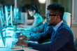 © pressmaster - Young serious businessman in eyeglasses and formalwear looking at screen of computer against his coworkers