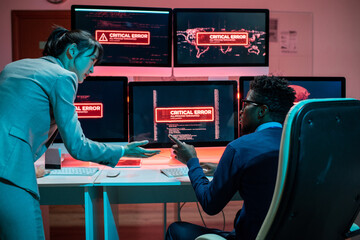 Poster - Two young intercultural programmers trying to solve problem with access to data while interacting in front of computers