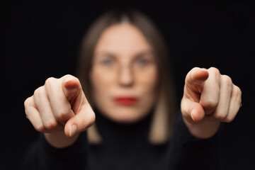 Close up woman portrait pointing fingers to camera, wearing glasses, with red lips, on black background with focuse face on fingers. You are the winner, I will find you. We are looking for you