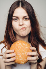 Wall Mural - woman with a hamburger in her hands a snack fast food close-up