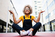 © Westend61 - Smiling woman meditating on footpath