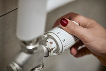 Woman Adjusting Thermostatic Radiator Valve Of Heating Boiler At Home