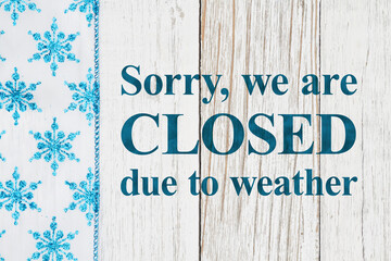 Wall Mural - Closed due to weather sign with blue and white snowflakes on with weathered wood