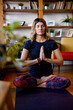 © chika_milan - A spiritual yogi woman sitting at home on a yoga mat in a lotus pose and praying. Yogi woman practicing yoga at home.