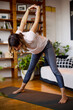 © chika_milan - A flexible middle-aged yogi woman standing on a yoga mat at home and practicing yoga. Yogi woman doing yoga exercises at home.