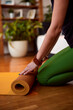 © chika_milan - Close up of yogi woman's hands rolling up a yoga mat at home. Hands rolling yoga mat.