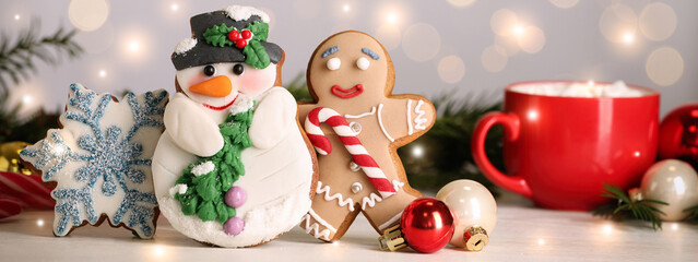 Wall Mural - Tasty Christmas cookies and decor on white table against blurred festive lights. Horizontal banner design