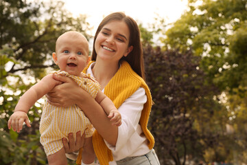 Canvas Print - Happy mother with adorable baby walking in park on sunny day, space for text