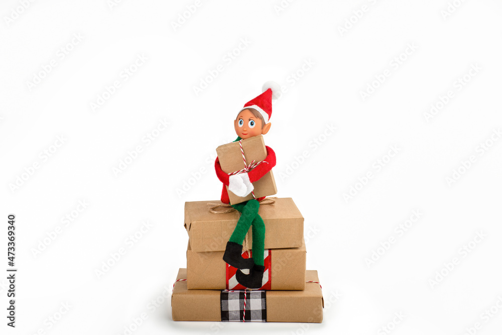 Christmas Elf sitting on a stack of gift boxes on an isolated white ...