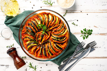 Vegan dish ratatouille made of vegetables in a baking dish on wihte wooden rustic background