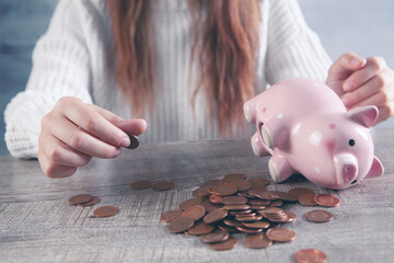 woman counting coins on the table and next to a piggy bank