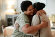 © Seventyfour - Portrait of senior African-American woman embracing daughter and smiling while welcoming guests for dinner party at home