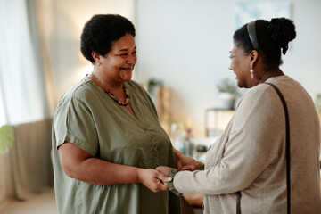 Wall Mural - Side view portrait of senior African-American woman welcoming family and guests for dinner party at home