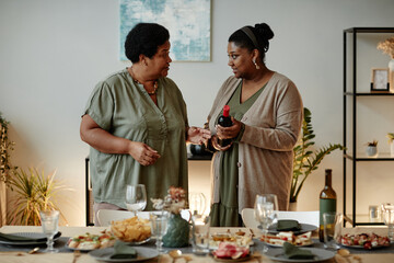 Wall Mural - Waist up portrait of two African-American women serving table for family dinner at home