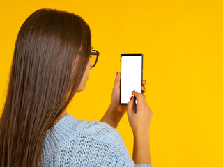 Poster - Phone mock up. Woman smartphone. Phone with blank white screen. Girl with phone with her back to camera. Place for your recommendation. Blank for advertising application. Cellphone in hands on yellow