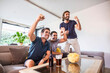 © Cavan Images - Three friends watching a soccer game at home drinking beer