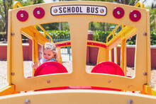 Little Girl Playing On A School Bus Toy At A Playground.