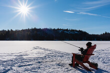 Teen Boy Ice Fishing On A Frozen Lake In Canada On A Winter Day.