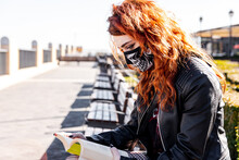 Gothic Girl With Orange Hair And Skull Face Mask Reading A Book
