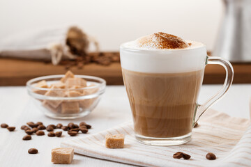 Latte coffee poured in layers with froth and a crispy chocolate top on a light kitchen table