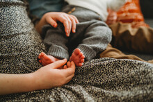 Close Up Of Older Child Holding Newborn Baby's Feet At Home