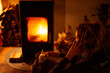 © Cavan Images - Young woman talks on phone at home by warm fire with small dog on lap