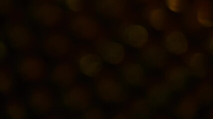 Wall Mural - Flaming diagonal motion of golden bokeh on a dark background. Smooth movement of yellow round bokeh with light leaks. Can be looped.