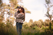 © Cavan Images - Young woman photographing with camera while standing in summer forest