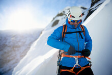 Male Ice Climber Making Last Minute Preparations Before Climbing