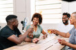 © PICHA - Friends playing cards while enjoying wine at home