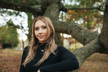 A Young Woman Stands Within A Large Oak Tree In A Park In Virginia