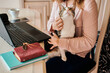 © Cavan Images - Young woman pets her cat while she is working from home