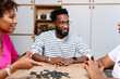 © PICHA - Friends playing domino game at home