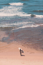 Boy Walking Towards The Ocean Carrying His Surfboard.
