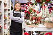 Positive owner of a flower shop prepares New Year decorations and arrangements