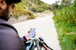 © Cavan Images - Man holding smartphone with road map, sitting on vintage motorbike