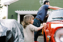 Little Girl Cleaning A Red Classic Car With Her Father Together
