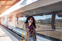 Happy Young African Girl Talking On Cell Phone At Train Station In Europe