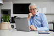 © Westend61 - Male professional with laptop looking away in office