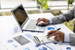 © kamiphotos - Businessman using a calculator to calculate numbers on a company's financial documents, he is analyzing historical financial data to plan how to grow the company. Financial concept.