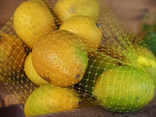 Macro of fresh lemons in a net on a wooden board