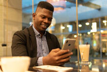 Elegant Black Guy Drinking Mocha And Using Smartphone In Coffee House