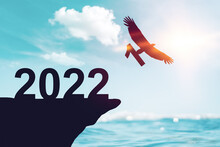 2022 New Year Concept With Eagle Bird Flying Away And Holding Number 1 On Sunset Sky Background At Tropical Beach.