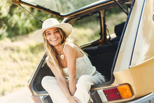 Blond Woman With Hat Sitting In Car Trunk