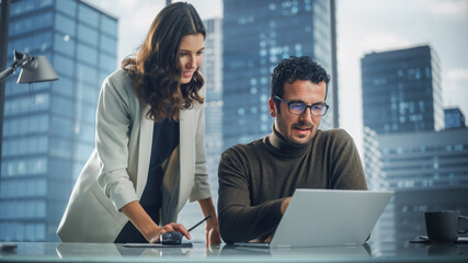 Company CEO and Top Manager Talking, Using Laptop Computer while in Big City Office. Two Successful Professional People Brainstorm, Find Solution to Their e-Commerce Software Investment Strategy