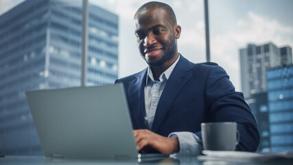 Aufkleber - Portrait of Successful Black Businessman in Tailored Suit Working on Laptop Computer in His Big City Office. Digital Entrepreneur does Data Analysis, Cloud Computing for e-Commerce Strategy assessment