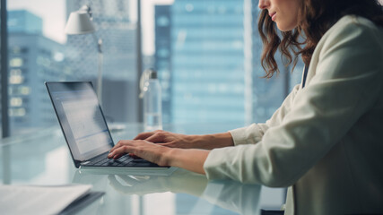 Wall Mural - Portrait of Young Successful Caucasian Businesswoman Sitting at Desk Working on Laptop Computer in City Office. Beautiful, Talented Corporate Manager Plan Social Media Strategy for e-Commerce Project