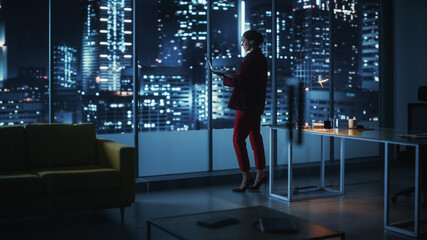 Poster - Successful Caucasian Businesswoman Wearing Stylish Suit Holding Laptop Standing in Big City Night Office. Female CEO Managing Environmental, Social and Corporate Governance for e-Commerce Project