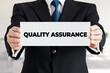 © Cagkan - Businessman shows a banner with the message quality assurance. Business product or service quality guarantee